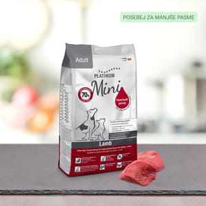 Vrečka PLATINUM Adult Lamb Suha Hrana za Pse za odrasle pse leži na temni površini poleg dveh kosov surovega mesa, z zamegljenim ozadjem in zeleno etiketo v zgornjem desnem kotu.